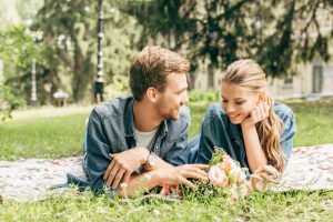 happy young couple lying on grass at park and flirting