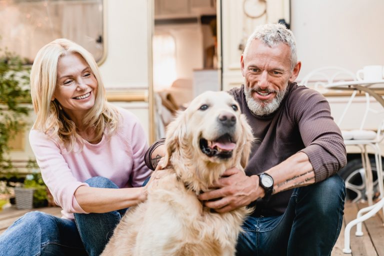 50s beautiful married couple spending time with their dog outside camper van